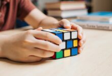 “Person solving Rubik’s Cube to improve memory, focus, and problem-solving skills – educational toy available at sandhai.ae.”