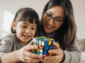 “Parent and child solving Rubik’s Cube together for educational fun and family learning.”